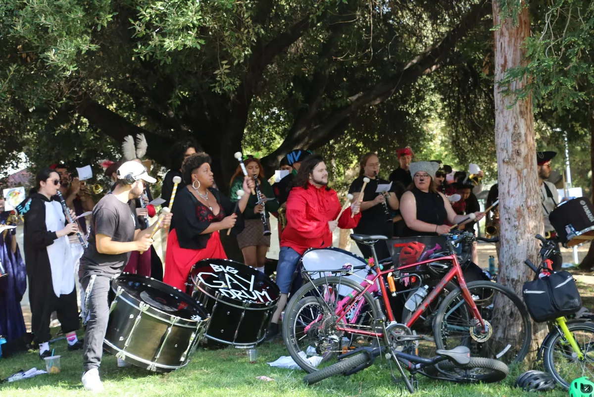 A group of drummers performs outdoors under the trees during the festival.
