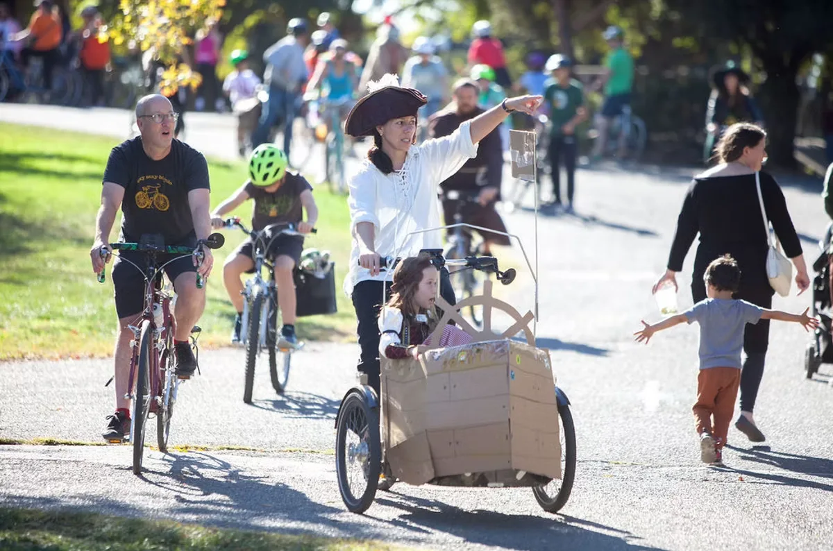 A family rides bikes together with a child in a decorated cargo trike.