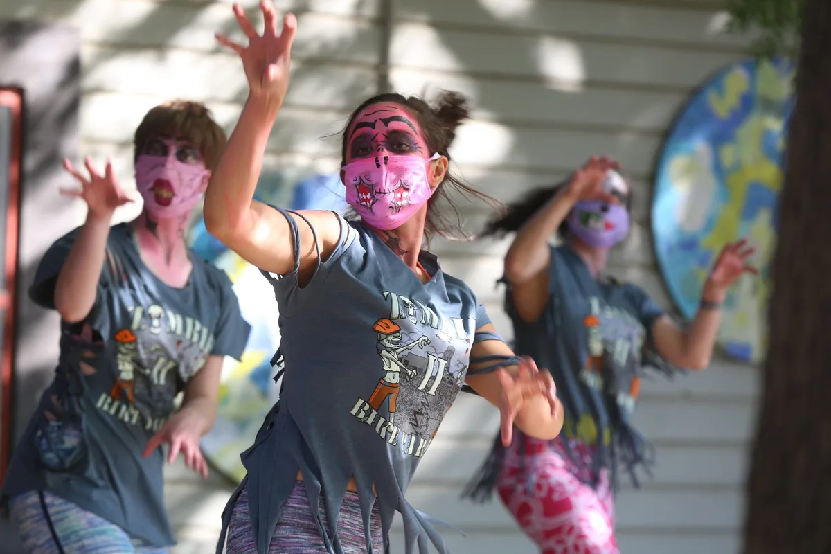 Two women in zombie makeup dance with their hands raised.