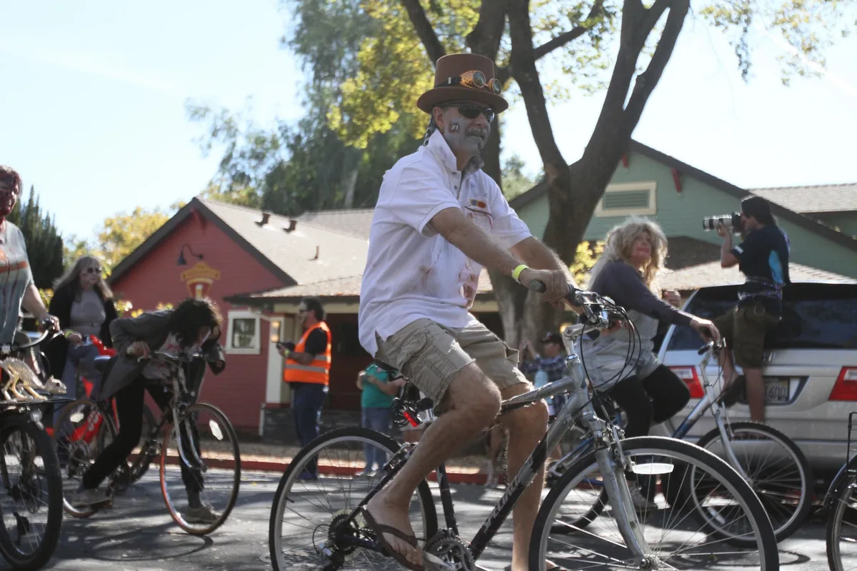 A rider pedals a cargo bike down a downtown street with others following.