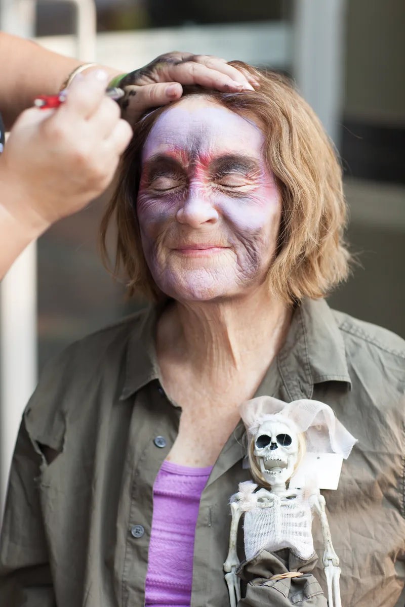 An artist applies Halloween face paint to a woman's face.