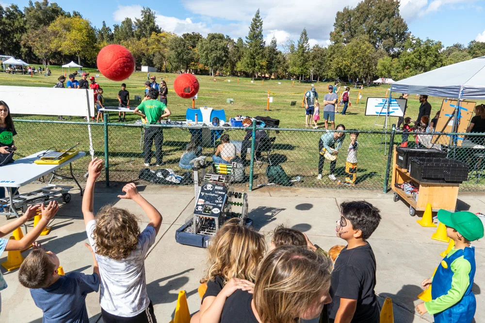 Kids toss rings at a carnival game booth in the park.