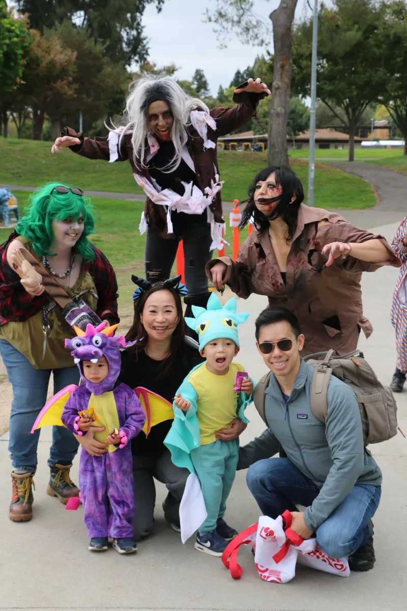 A family in coordinated Halloween costumes gathers for a group photo in the park.