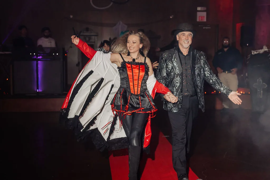 Three guests in elegant Halloween costumes pose on the red carpet at the Zombie Ball.