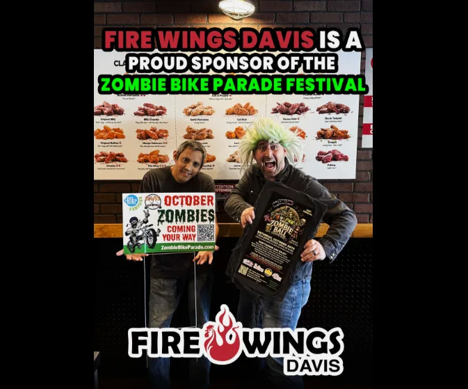 Two men hold a sign announcing Fire Wings Davis as a festival sponsor.