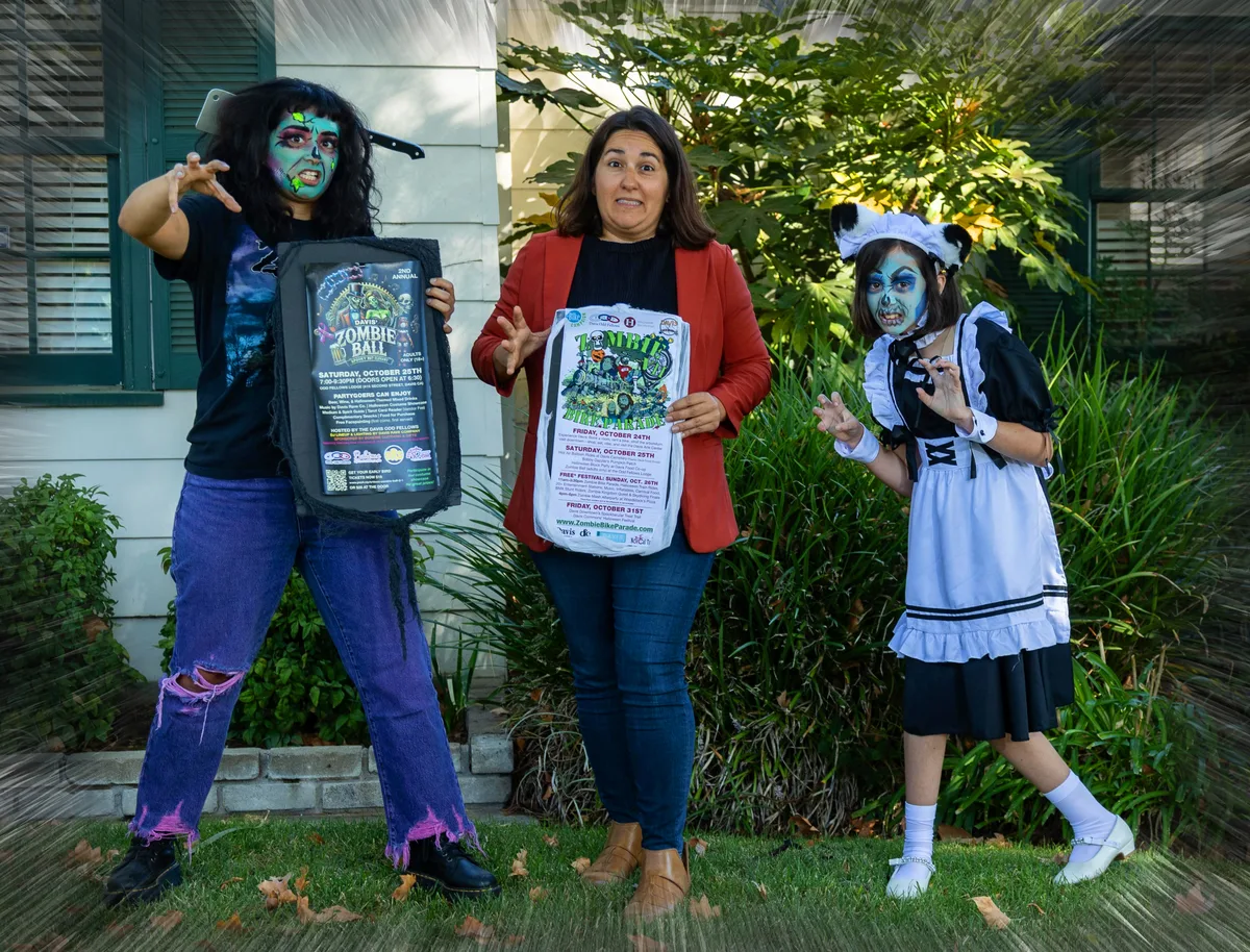 Two costumed women hold festival flyers on a front porch.