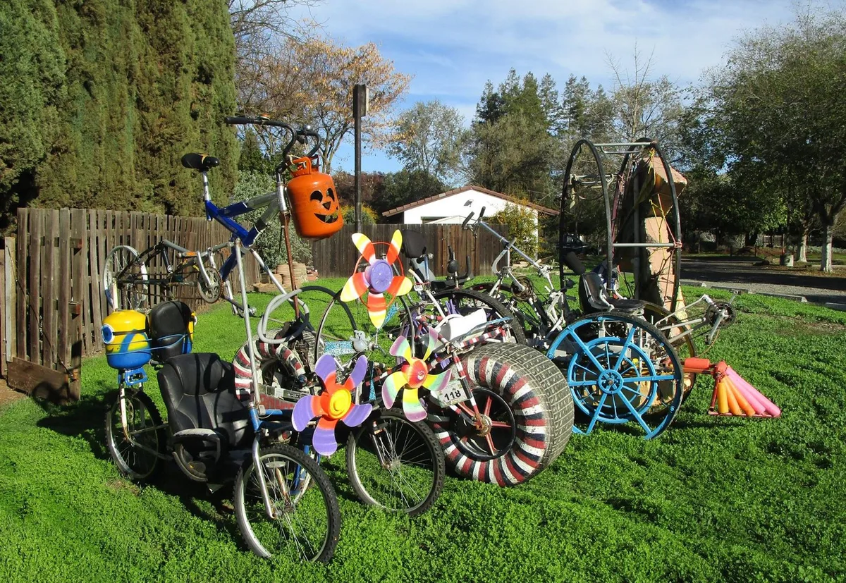 Whimsical art bicycles decorated with pumpkins and pinwheels sit on a lawn.