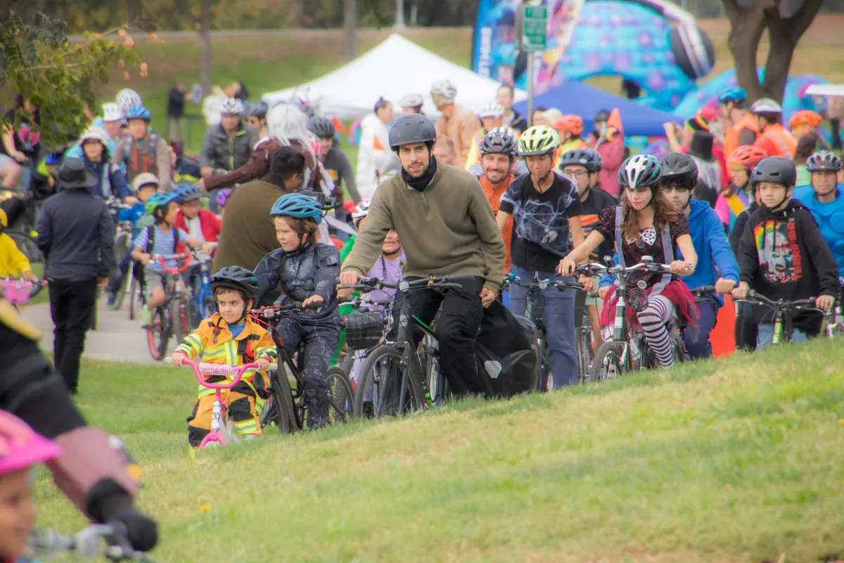 A large crowd of families and cyclists gathers on the grass at the start of the festival.