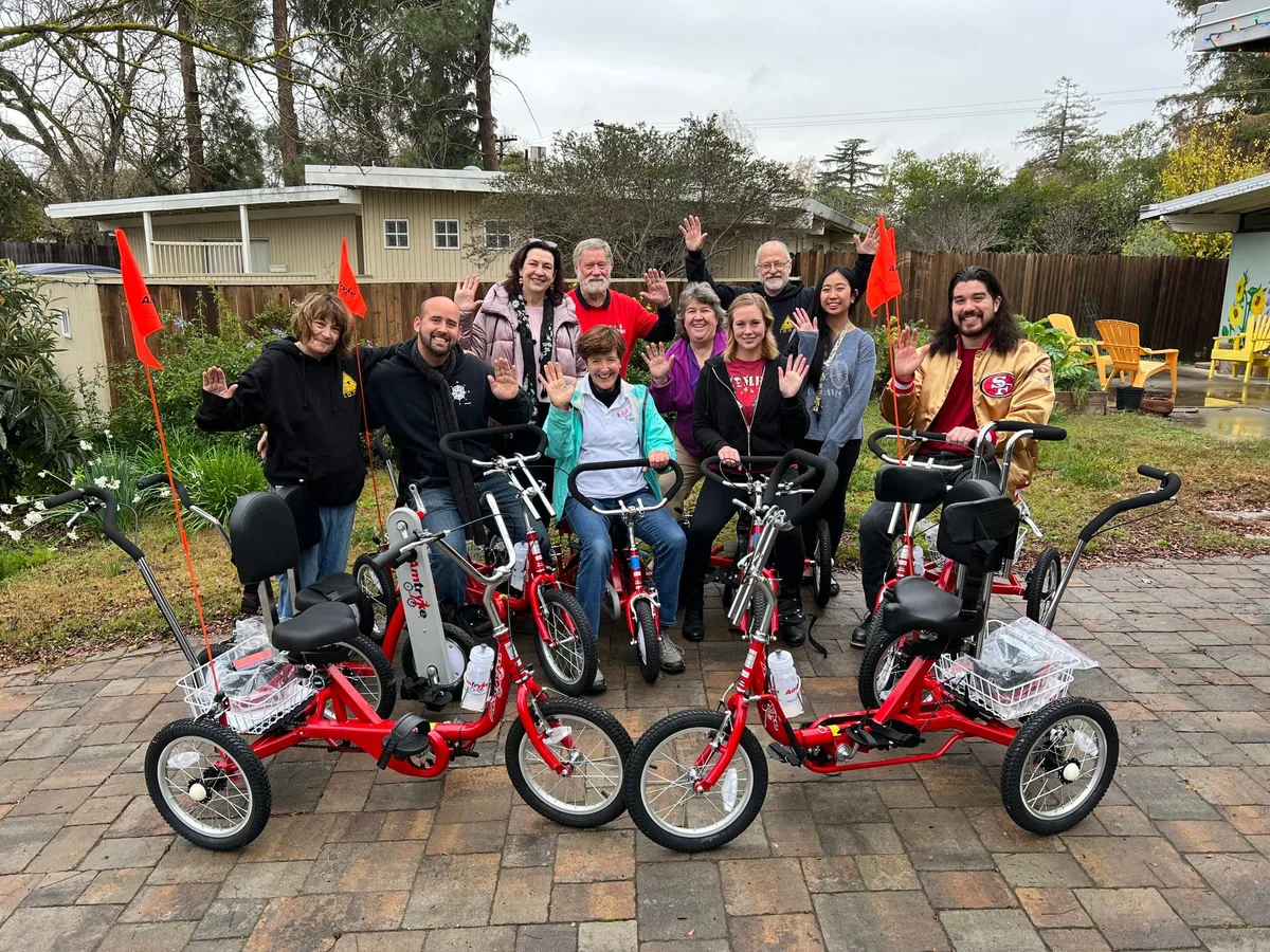 A family rides a red multi-seat surrey cycle down the park path.
