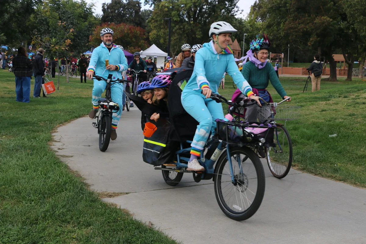 A family in matching blue costumes pedals together along the park path.