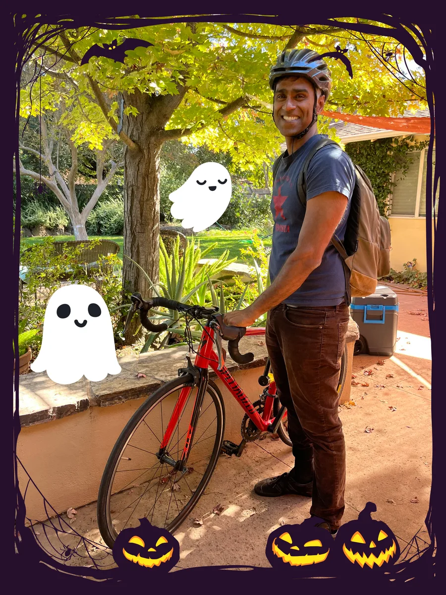 A man stands with his bike beside a cartoon ghost graphic overlay.