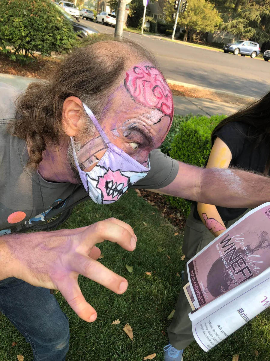 A close-up shows a man's face with detailed zombie prosthetic makeup.