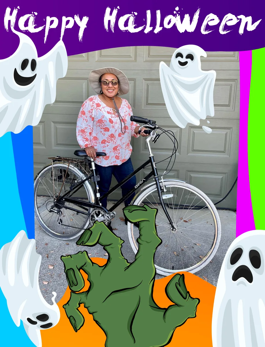 A woman stands with her bike beside ghost decorations on a garage door.