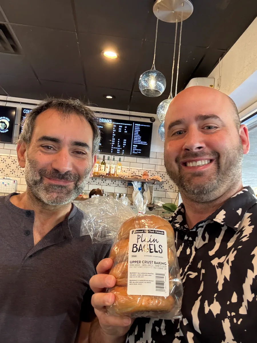 Two men smile for a selfie inside a restaurant.