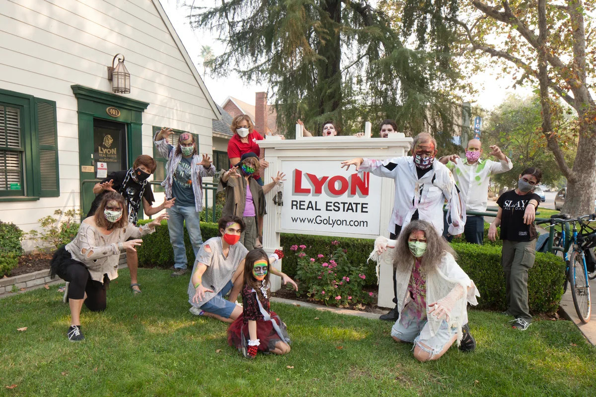 Zombie-costumed guests pose in front of the Lyon Real Estate sign.