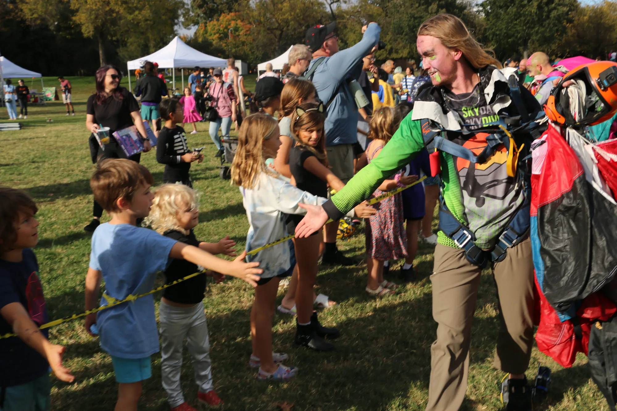 A Skydance Skydiving jumper high-fives kids waiting in line.
