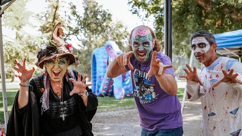 A witch and two zombies in vivid makeup reach toward the camera with clawed hands.