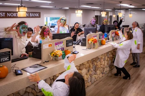 The bank teller line again with everyone throwing their hands up in a zombie pose, two in white lab coats on the customer side of the counter.