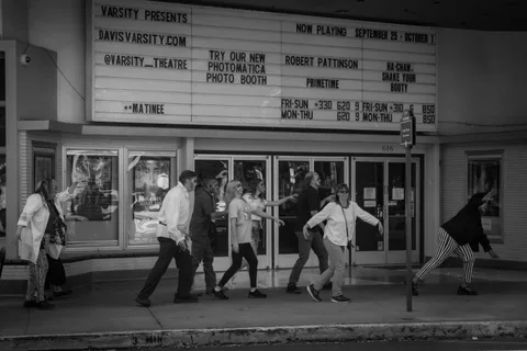 Black and white: the zombie group strung out along the sidewalk beneath the Varsity Theatre marquee, arms reaching ahead of them.