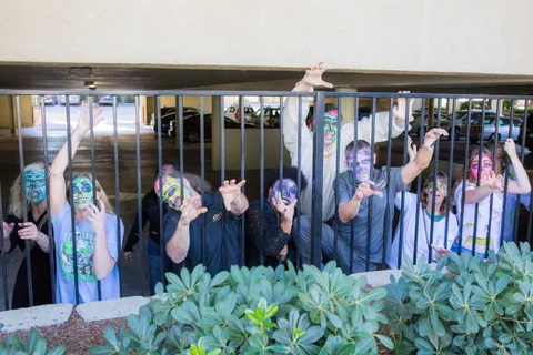 The same railing shot from further back, zombies reaching over and through the bars along the length of the fence.