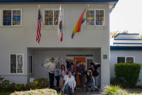 The group gathers in the doorway of International House Davis, below the American, California and Pride flags.