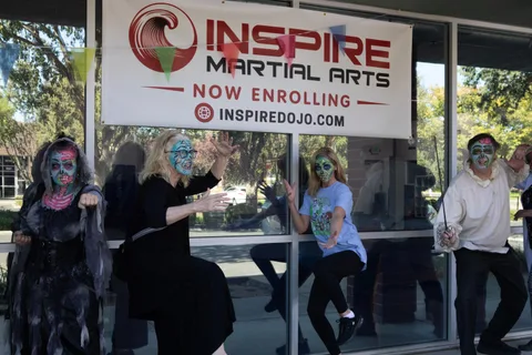 Four zombies pose along a studio window beneath an Inspire Martial Arts now enrolling banner.